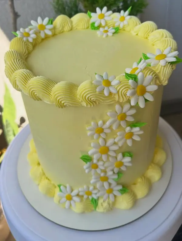 Torta amarilla con margaritas de crema y borde de merengue