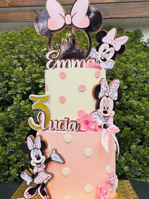 Torta de dos pisos de Minnie Mouse en rosado y blanco con nombres en topper